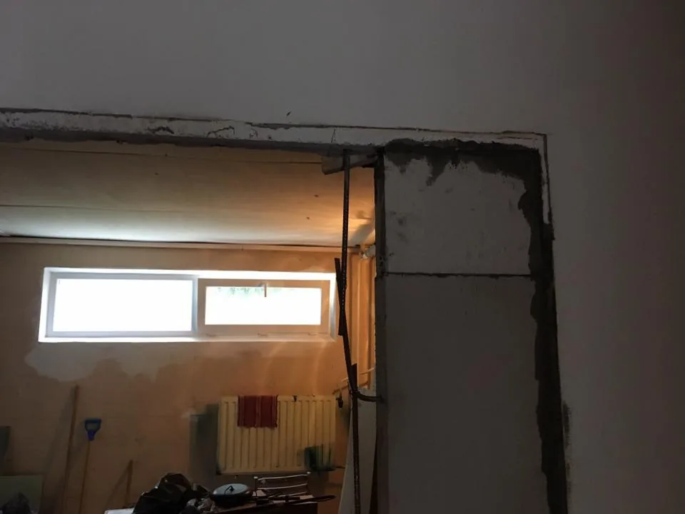 Dverný otvor pripravený na osadenie, za ním miestnosť s oknom