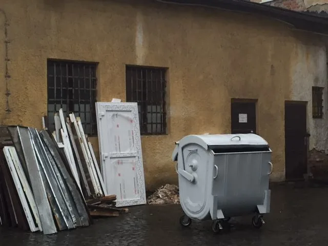 Vymontované staré okenné krídla opreté pri kontajneri