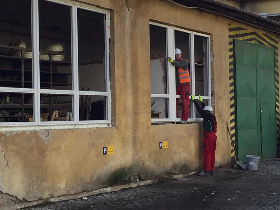 Pracovníci osádzajú nové okno do otvoru