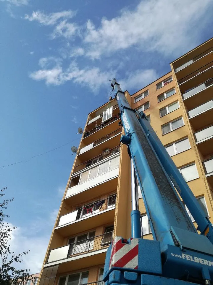 Rameno žeriava vystreté pozdĺž fasády bytového domu